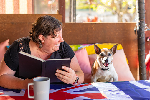 Happy Mature Woman Reading at Home with Her Dog