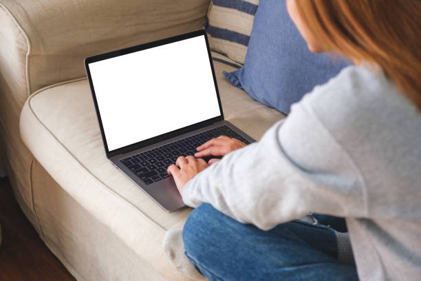 istock Mockup image of a woman working and typing on laptop computer with blank screen on sofa at home 1456093405