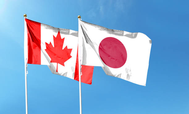 istock Japan and Canada flags against cloudy sky. waving in the sky 1456099252