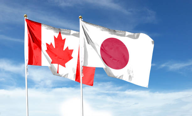 istock Japan and Canada flags against cloudy sky. waving in the sky 1456099356