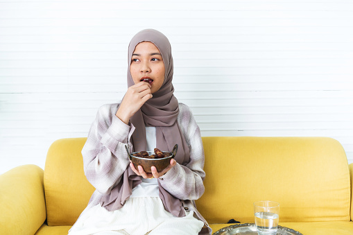 Young muslim woman eating date to break fast at home