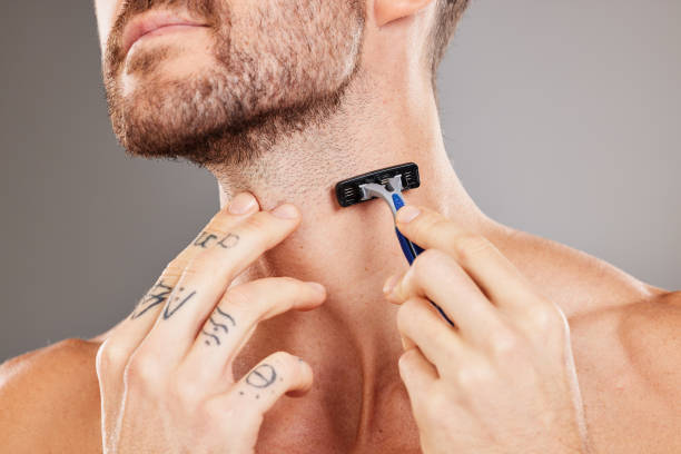 Grooming, beard and man shaving hair for skincare, wellness and health against a grey studio background. Dermatology, hygiene and hands of a model with a razor to shave neck for a fresh treatment aseo, barba y cabello afeitado para el cuidado de la piel, el bienestar y la salud contra un fondo gris de estudio. dermatología, higiene y manos de una modelo con una maquinilla de afeitar para afeitarse el cuello para un nuevo tratamiento
