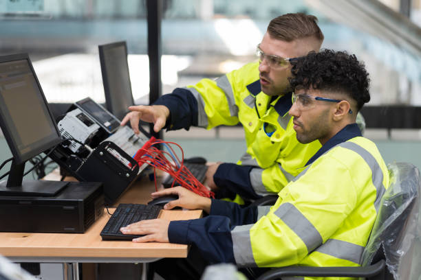 two male engineers using desktop computer training programmable logic controller or programmable controller in the manufacturing automation and robotics academy room. industrial computer concept - estagiário imagens e fotografias de stock