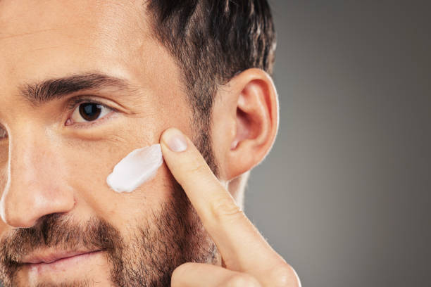 istock Face, skincare and beauty with a man model using treatment in studio on a gray background for wellness. Finger, cosmetics and antiaging with a handsome young male inside to apply lotion to his cheek 1456108632