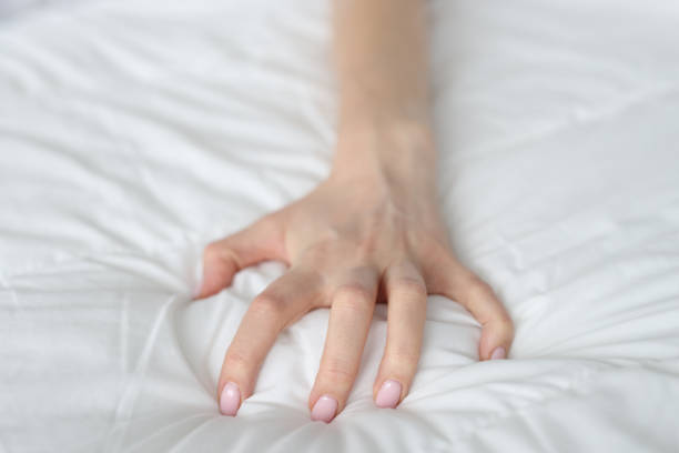 istock Strongly clenched female hand on sheet on bed 1456108751