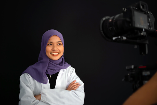 Smiling muslim teenage girl posing on black background