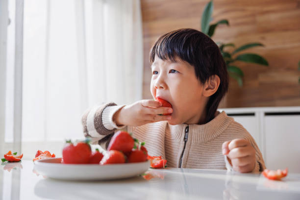 istock five years old boy eating strawberry 1456115007