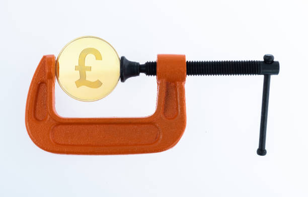 оранжевый зажим с монетой в фунте - credit crunch squeezing vise grip british currency стоковые фото и изображения