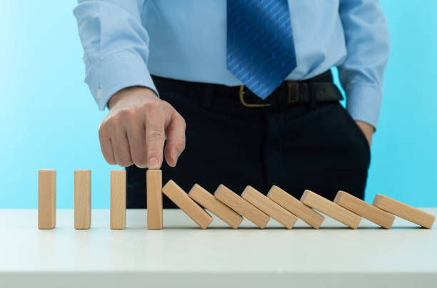 istock Businessman hand stopping the dominos falling 1456117733