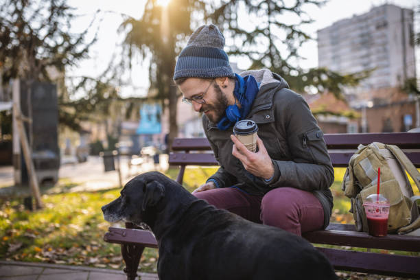 Photo of a young man on a winter day drinks his take away coffee in a city park.
