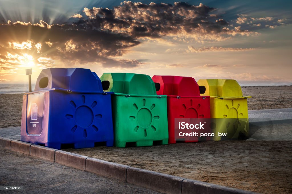 plastic garbage bins plastic multicolor containers for recycling on the beach, tin cans, paper, glass, plastic, at sunset Beach Stock Photo