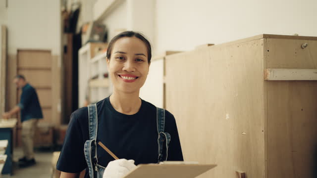Portrait of Asian female carpenter working in a furniture workshop.