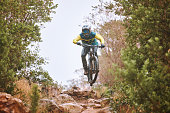 Mountain bike, sports and fitness with a man adrenaline junkie riding in the woods or forest in nature. Sky, training and exercise with a male athlete on a bike for trail riding or adventure