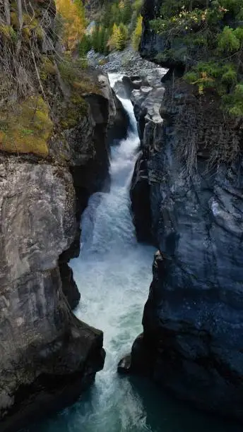 Photo of Vertical view of a waterfall in Nairn Falls Provincial Park, surrounded by mountains and forest