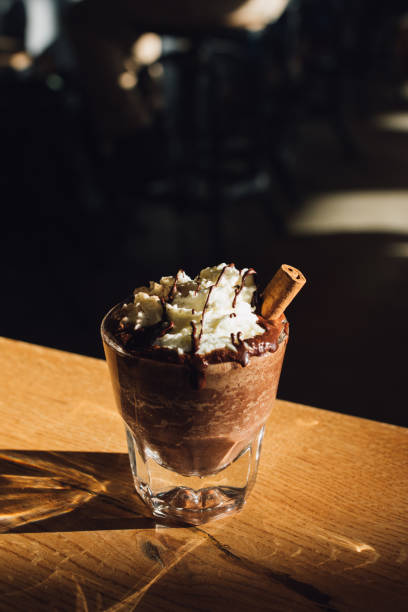 istock Hot chocolate topped with whipped cream, chocolate drizzle, cinnamon stick on wood table 1456126578