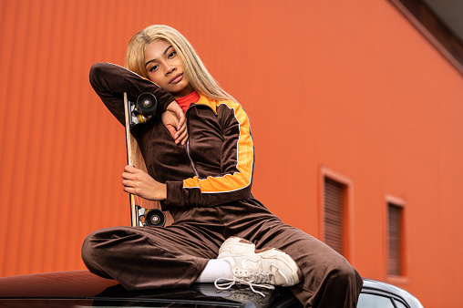 A young African American woman with long blonde hair and sportswear on an orange background