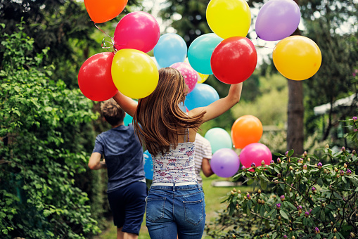 Happy three teenage kids with balloons running in the backyard\nCanon R5