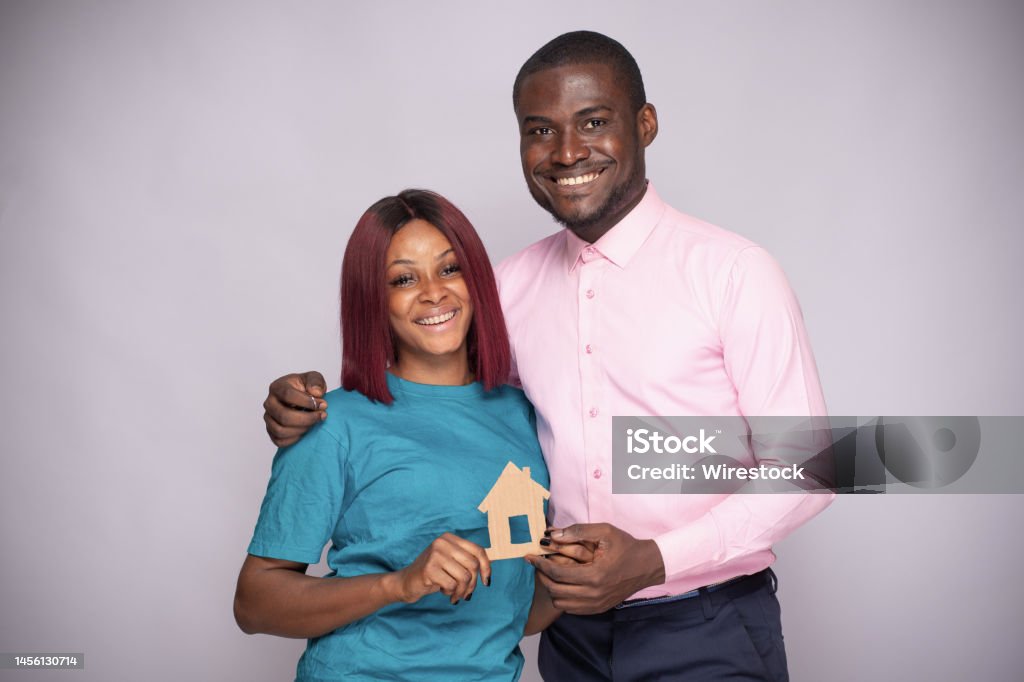 Happy African couple holding a smal wooden house together. Family concept A happy African couple holding a smal wooden house together. Family concept Adult Stock Photo