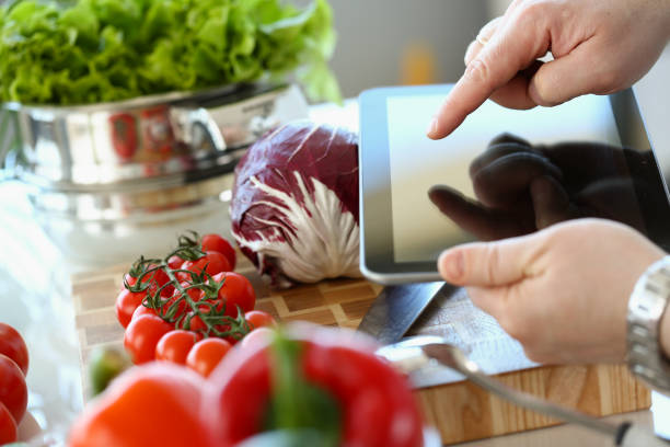 istock Person holds tablet and is going to cook vegetables 1456131002