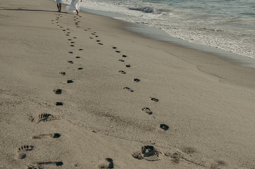 A closeup shot of foot prints of the couple on sand on a sunny day