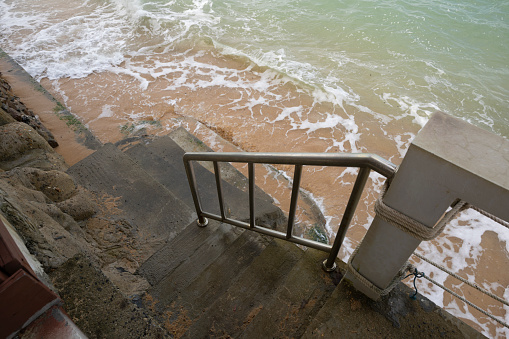 Steps to the sea at high tide with very little beach in strong wind and bad weather, Mae Nam Beach, Koh Samui
