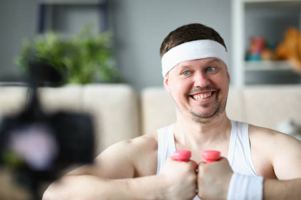 istock Smiling man is holding dumbbell and looking into camera 1456134994