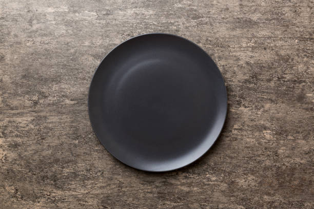 istock Top view of black plate on cement background. Empty space for your design 1456135172