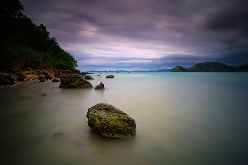 Horizontal long exposure shot of a rock in a water during a cloudy day in Kelor island in Komodo National Park