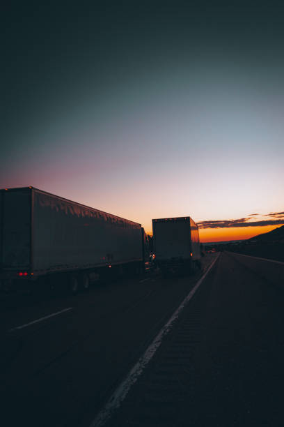 istock Trucks driving through an asphalt road with a scenic sunset horizon 1456140540