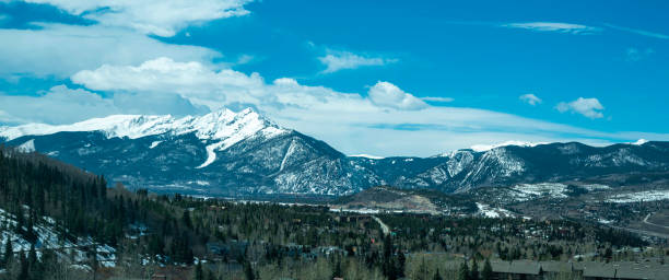 istock Breathtaking view of snowy mountains over the fields with dense-growing trees against a cloudy sky 1456143259