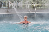 Woman in outdoor thermal pool with hydromassage.