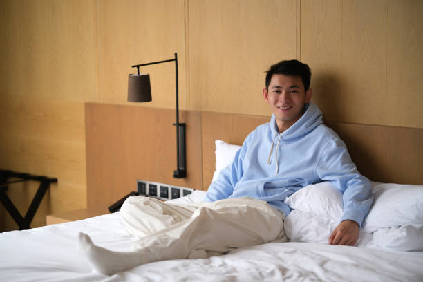 istock smile Asian young man sit on bed 1456150108