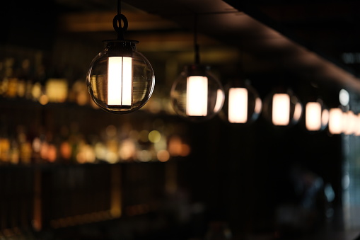 a row of pendant lights at dark cafe bar with colorful bokeh