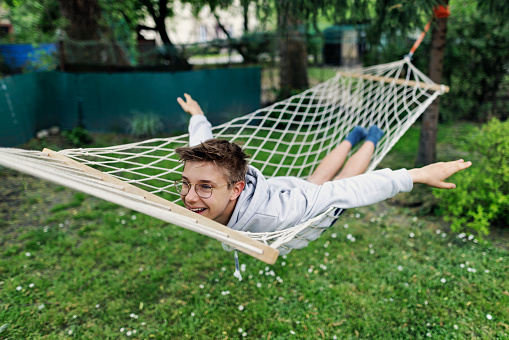 Teenage boy relaxing and playing on hammock on a spring day
Canon R5