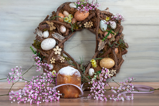 Easter background with colored Easter wreath and blooming flowers. Kulich. Easter composition.