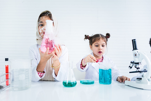 Little girl students doing science experiments in a classroom