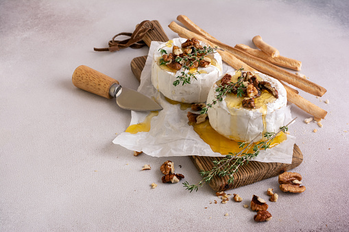 Gourmet meal of white brie cheese or camembert with thyme, walnut, honey and grissini bread stick for tasty dinner