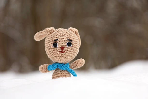 istock Knitted bunny in a snow on blurred forest background, greeting card 1456155516