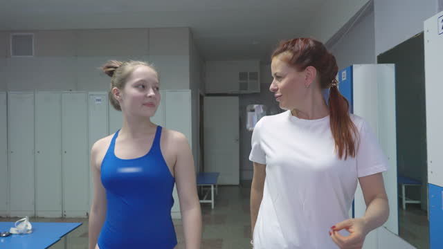 Mature Woman and teen girl are walking in the locker room of the swimming pool.