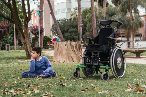 istock Child with a disability relaxing sitting on a grass in a public park. 1456161848