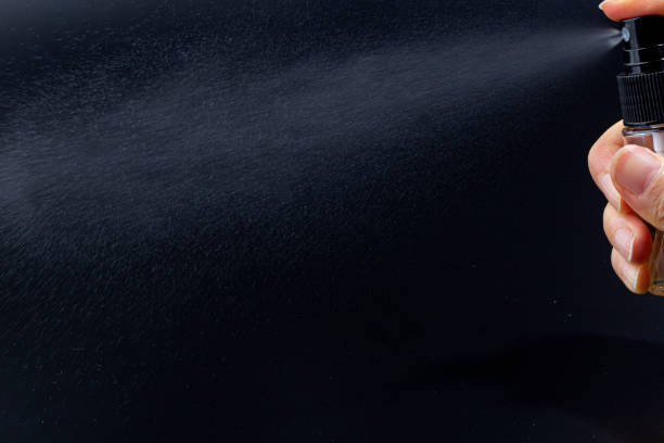 istock hand holding small spray bottle and spraying on black background 1456162267