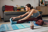 A woman in leggings doing stretching exercises at home