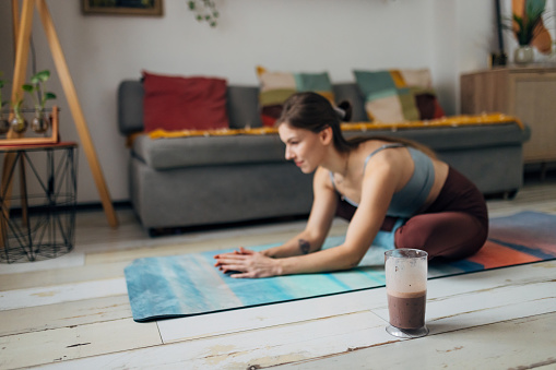 Female athlete does a workout at home, after which she will drink a healthy milkshake she made