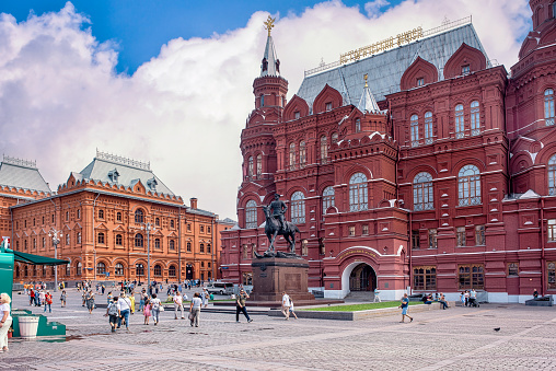 Moscow, Russia - August 10, 2021: Red brick Russian State Historical Museum facade with the street square on blue sky background.