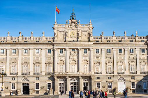 Madrid, Spain - Dec 10th, 2022: The Madrid Royal Palace in Baroque style, in the past used as the residence of the King of Spain, Plaza de la Armeria, Community of Madrid, Spain, southern Europe. A large number of tourists visit the famous monument on a sunny December winter day.