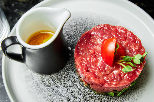 Veal tartare with Tomatoes on a white plate in a restaurant. Close-up, selective focus
