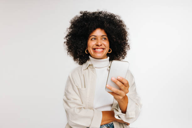 istock Thoughtful young woman holding a smartphone in a studio 1456164529