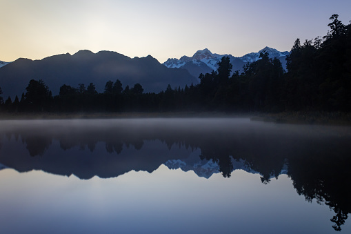 was a very exciting morning at the famous Lake Matheson new Fox Glacier in South Island of New Zealand. The mist covered the lake completely and clear sky created a silhouette of Mount Cook and adjacent alps ranges.