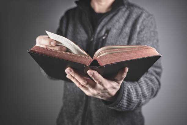 istock Man holding reading holy bible with gray background 1456166369
