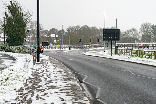 The inner ring road in Huntingdon, Cambridgeshire, England, UK.  There is a delivery driver on the road with snow covering the pavement.